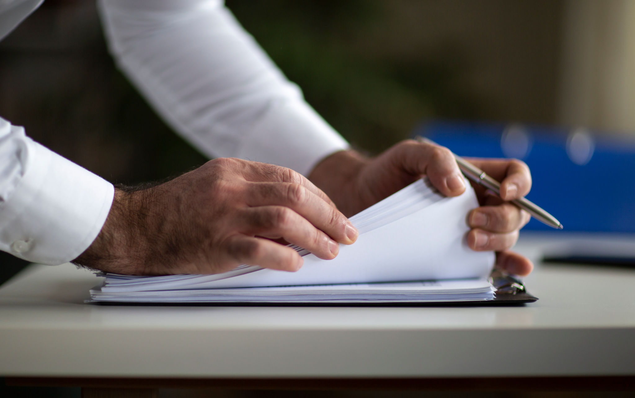 Male arm in suit offer insurance form clipped to pad